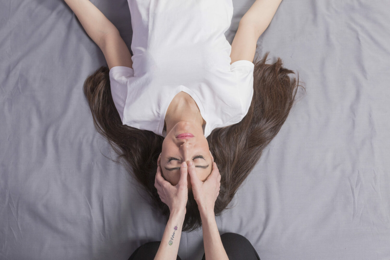 Young woman lying while enjoying thai massage by professional woman at spa and wellness center